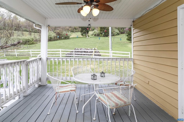 wooden terrace with a lawn and ceiling fan