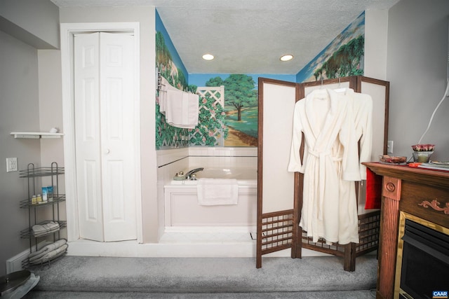 bathroom featuring a fireplace, a bath, and a textured ceiling