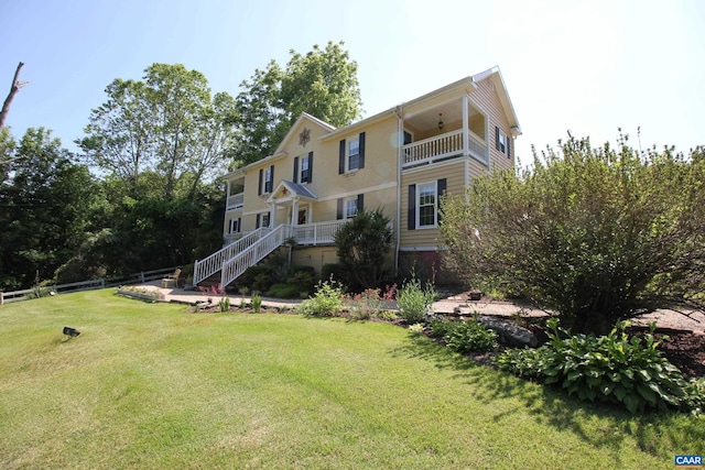 back of property with a balcony and a lawn