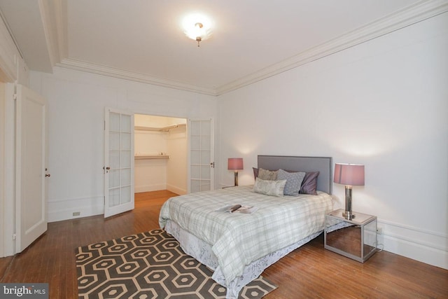 bedroom featuring crown molding, a closet, dark hardwood / wood-style floors, and a spacious closet