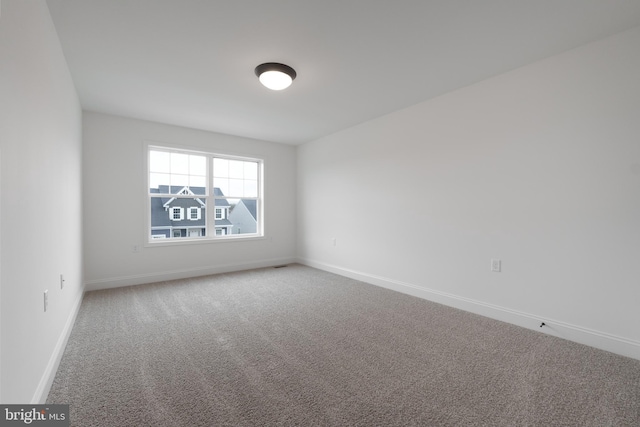 unfurnished room featuring carpet floors, visible vents, and baseboards