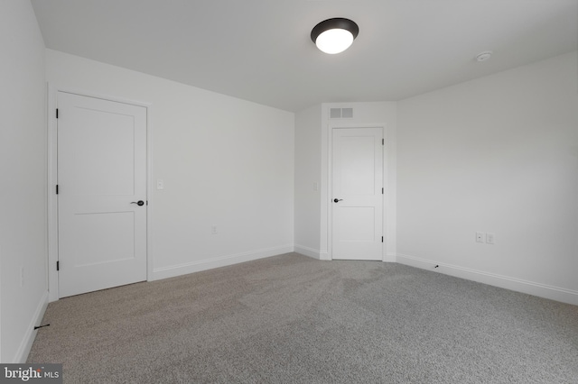carpeted spare room featuring visible vents and baseboards