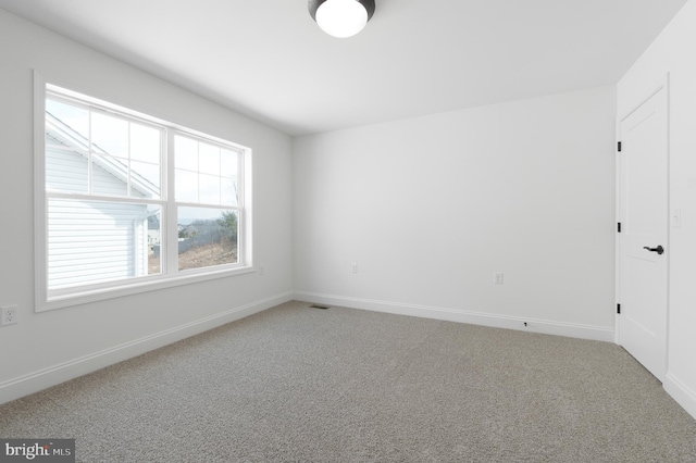 empty room featuring carpet flooring, visible vents, and baseboards
