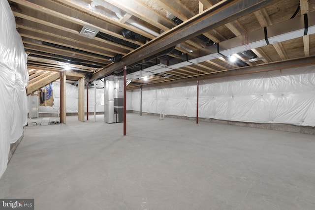 unfinished below grade area featuring water heater, visible vents, and heating unit