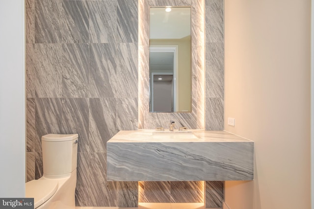 bathroom with tile walls, toilet, and sink