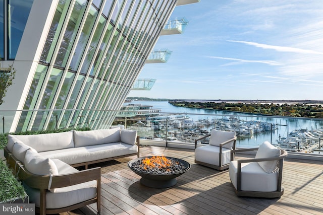 wooden deck featuring an outdoor living space with a fire pit and a water view