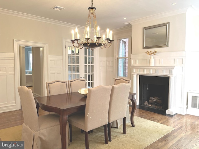 dining area with a notable chandelier, ornamental molding, and light wood-type flooring