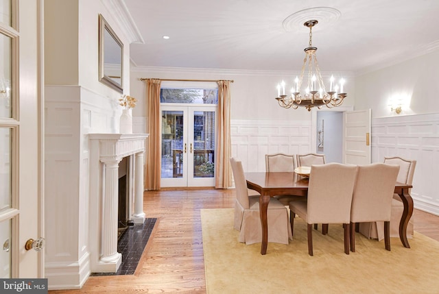 dining area featuring french doors, ornamental molding, a chandelier, and light hardwood / wood-style flooring