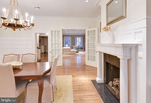 dining space featuring french doors, an inviting chandelier, ornamental molding, and light wood-type flooring