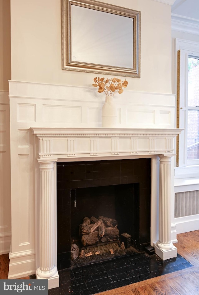 interior details with crown molding, a tile fireplace, and dark hardwood / wood-style flooring