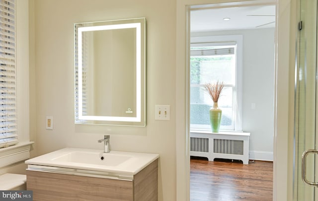 bathroom with vanity, hardwood / wood-style floors, and radiator