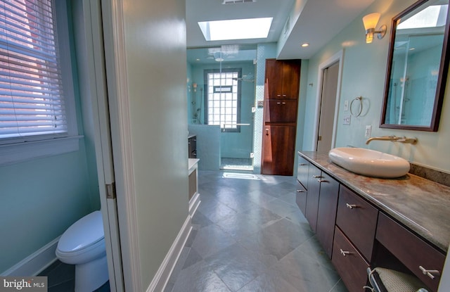 bathroom featuring toilet, a washtub, a skylight, tile floors, and vanity