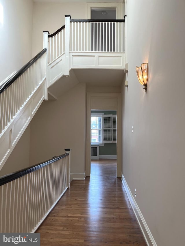 corridor featuring dark wood-type flooring and a towering ceiling