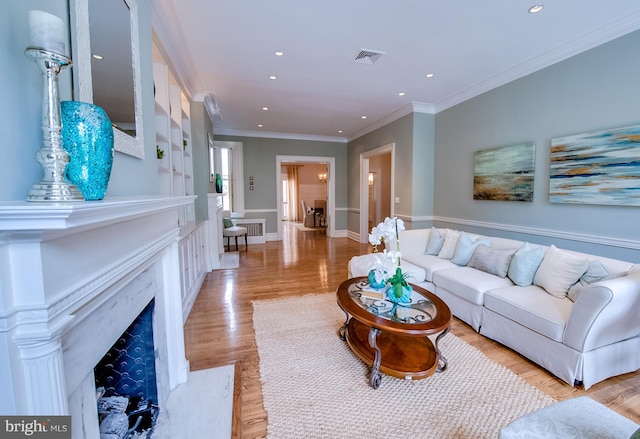 living room featuring ornamental molding, light hardwood / wood-style floors, and a premium fireplace