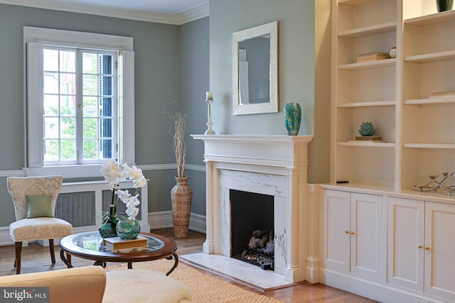 living area featuring a premium fireplace, plenty of natural light, ornamental molding, and light hardwood / wood-style flooring