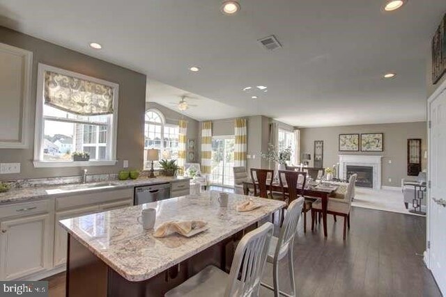 kitchen with white cabinetry, light stone counters, sink, and a kitchen island