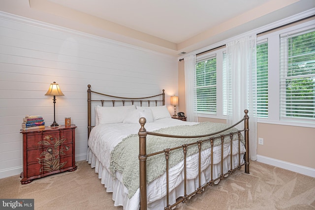 bedroom featuring wooden walls and light colored carpet