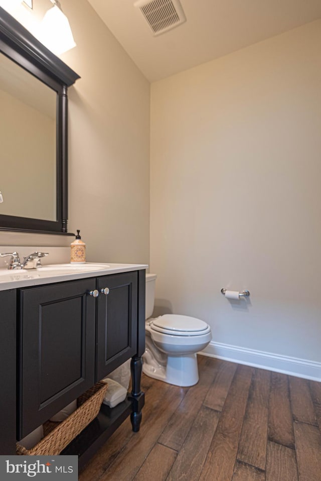 bathroom with wood-type flooring, vanity, and toilet