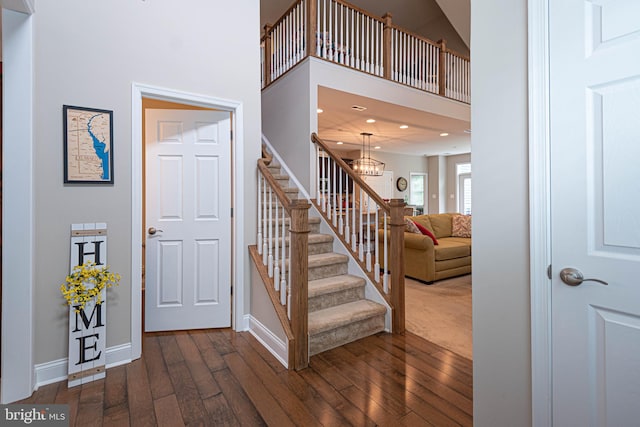 stairway featuring a high ceiling, a chandelier, and hardwood / wood-style flooring