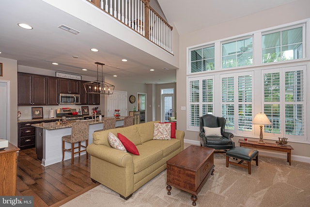 living room featuring light hardwood / wood-style flooring, a towering ceiling, an inviting chandelier, and sink