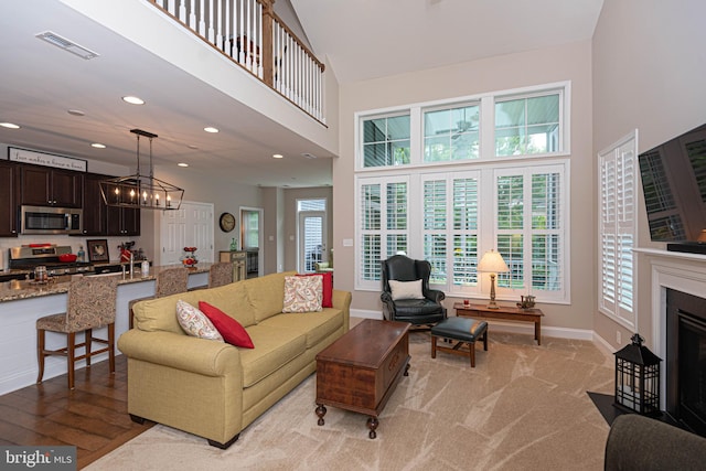 living room with a notable chandelier, a towering ceiling, and light hardwood / wood-style floors