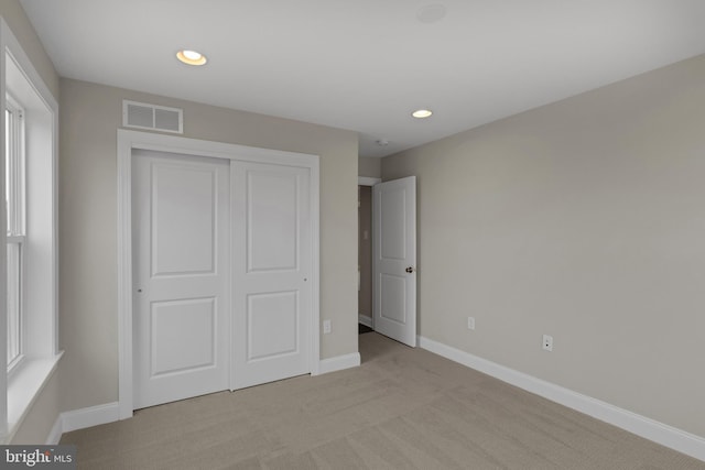 unfurnished bedroom featuring a closet, light colored carpet, and multiple windows