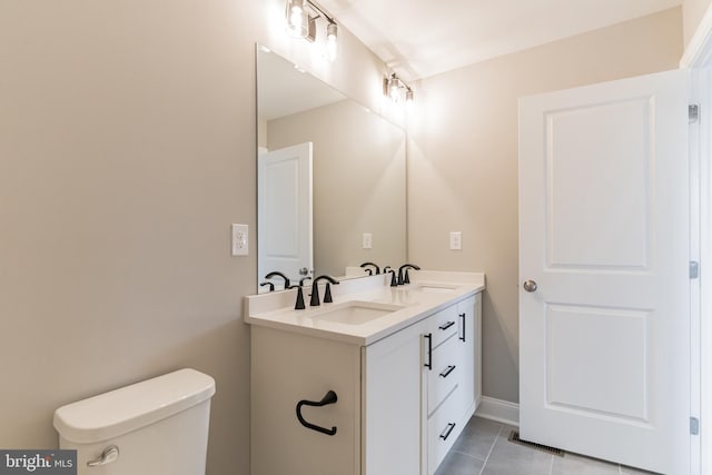 bathroom with toilet, vanity, and tile patterned floors