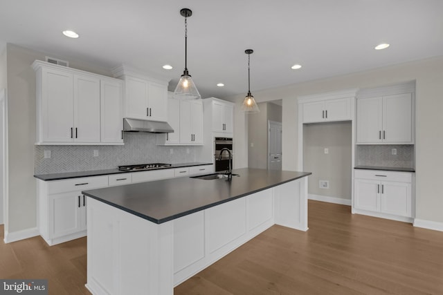 kitchen featuring white cabinets, sink, an island with sink, and light hardwood / wood-style flooring