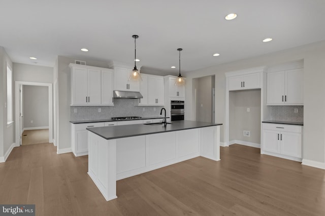 kitchen with white cabinets, an island with sink, light hardwood / wood-style flooring, and sink