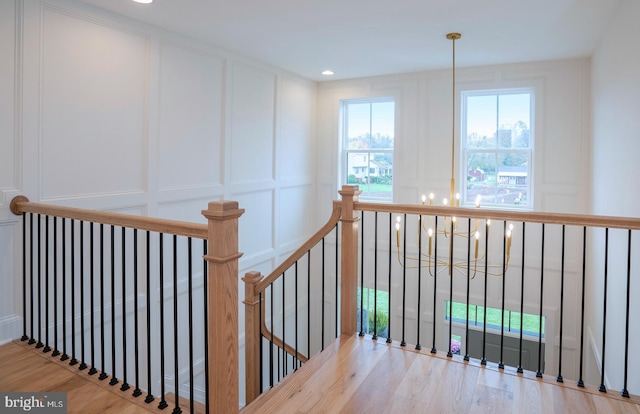 stairway featuring hardwood / wood-style floors and an inviting chandelier