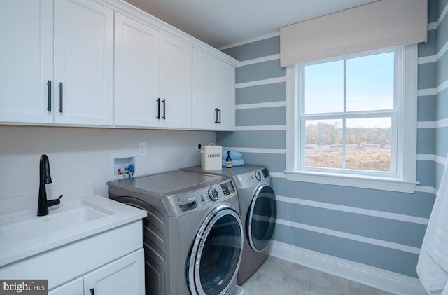 clothes washing area with cabinets, sink, and washing machine and clothes dryer