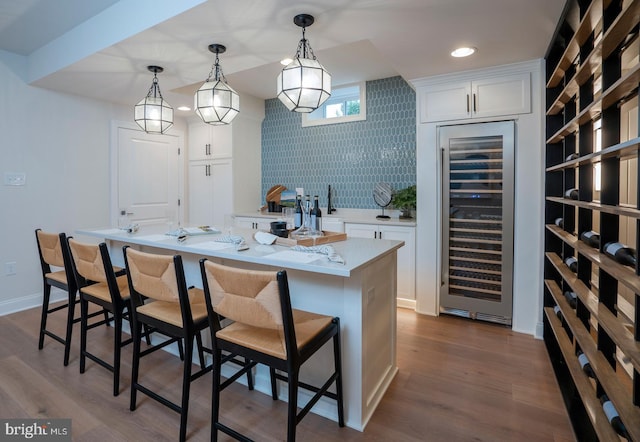 interior space featuring decorative light fixtures, white cabinetry, dark wood-type flooring, and beverage cooler