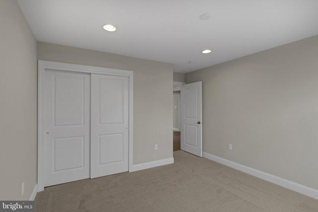 unfurnished bedroom featuring light colored carpet and a closet