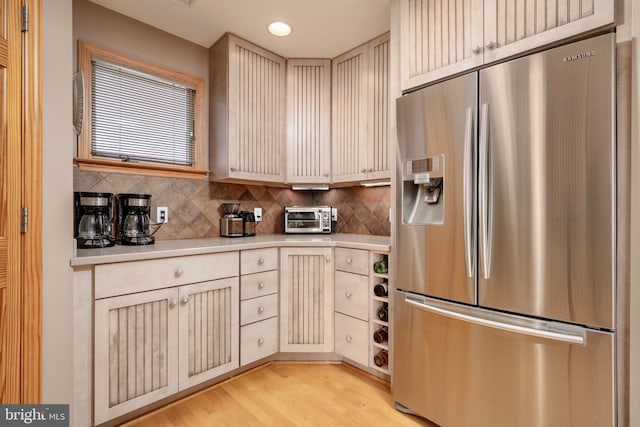 kitchen with tasteful backsplash, light hardwood / wood-style floors, and stainless steel fridge with ice dispenser