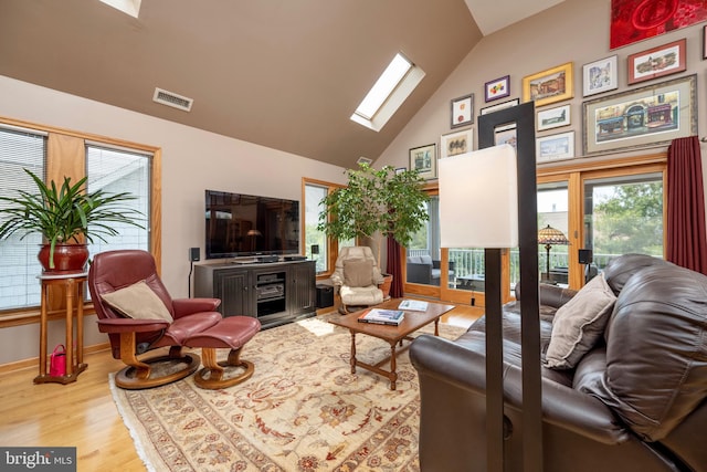 living room featuring a skylight, high vaulted ceiling, and light hardwood / wood-style floors