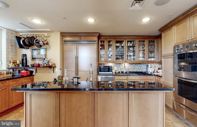 kitchen with dark stone counters, tasteful backsplash, a kitchen island, built in appliances, and light tile floors