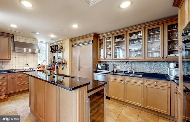 kitchen featuring tasteful backsplash, wall chimney range hood, paneled fridge, dark stone countertops, and light tile floors