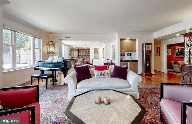 living room with ornamental molding, a chandelier, and hardwood / wood-style flooring