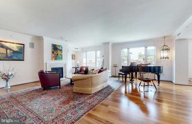 living room with crown molding, light hardwood / wood-style floors, and a chandelier