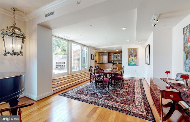 dining area featuring ornamental molding, a notable chandelier, and light hardwood / wood-style flooring