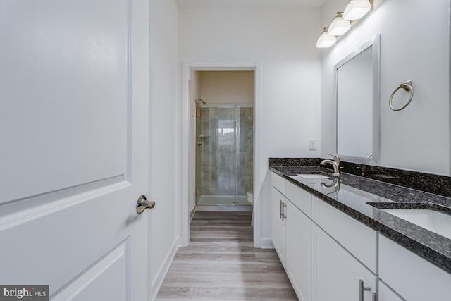 bathroom with vanity, toilet, tiled shower, and wood-type flooring