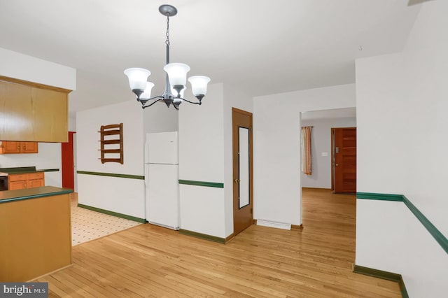 kitchen featuring white refrigerator, light hardwood / wood-style floors, decorative light fixtures, and a notable chandelier