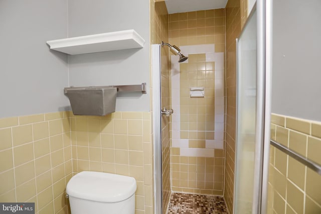 bathroom with tile walls, toilet, and tiled shower