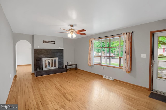 unfurnished living room with light hardwood / wood-style flooring, ceiling fan, baseboard heating, and a brick fireplace