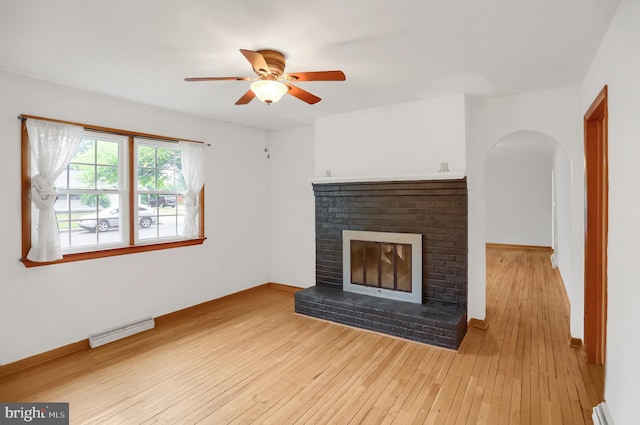 unfurnished living room featuring a baseboard heating unit, a fireplace, ceiling fan, and light hardwood / wood-style flooring