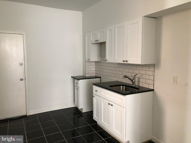 kitchen with white cabinetry, decorative backsplash, dark tile patterned flooring, and sink