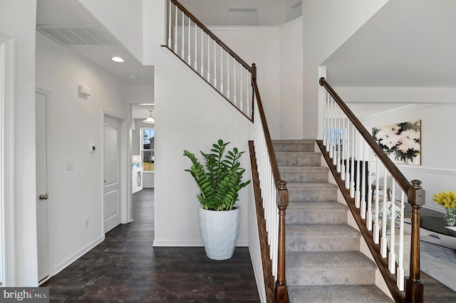 stairs featuring a high ceiling and dark hardwood / wood-style floors