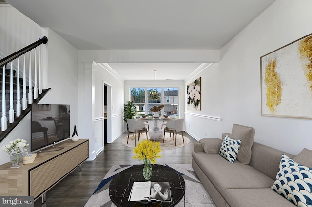 living room with dark hardwood / wood-style flooring, a notable chandelier, and ornamental molding