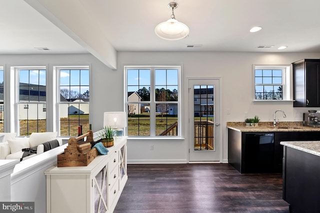 interior space with hanging light fixtures, dark hardwood / wood-style floors, sink, black dishwasher, and light stone counters