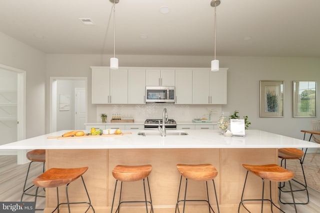 kitchen featuring a large island with sink, sink, and white cabinets